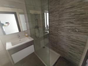 ein Bad mit einer Dusche, einem Waschbecken und einem Spiegel in der Unterkunft Gozo Spacious 3 Bathroom Apartment in Nadur