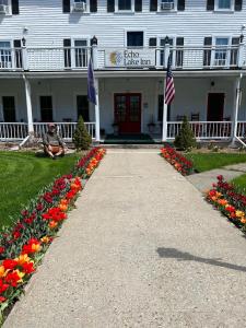 um homem sentado em frente a um edifício branco com flores em Echo Lake Inn em Tyson