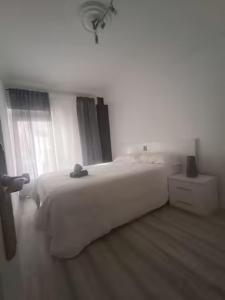 een witte slaapkamer met een groot bed en een raam bij Apartamento San Antón in Huesca