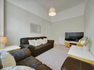 a living room with a couch and a tv at Hayfield Apartment in Oban