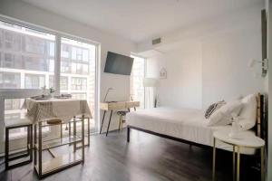 a white bedroom with a bed and a table and a desk at Brand New Studio in Heart of Downtown Toronto J8 in Toronto