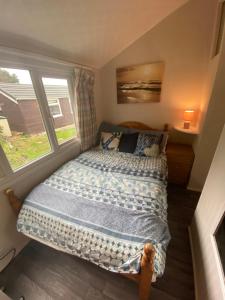 a bed in a small room with a window at Chalet 5 Clarach Bay in Aberystwyth
