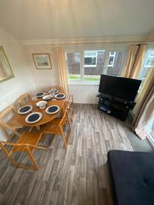 a room with a table and chairs and a television at Chalet 5 Clarach Bay in Aberystwyth