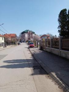 an empty street with a fence and cars on the road at Apartman Gaga in Donji Komren