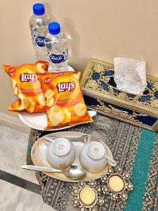 une table avec deux sacs de chips et des bouteilles d'eau dans l'établissement Mohalla Rooftop Retreat, à Karachi
