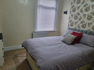 a bed with red pillows in a bedroom with a window at Private Rooms in Croydon London in Thornton Heath
