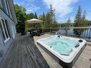 a jacuzzi tub on the deck of a house at Stunning waterfront getaway w hot tub sleeps 14 in Sainte-Cécile-de-Masham