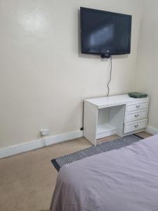 a bedroom with a tv on the wall and a bed at Private Rooms in Croydon London in Thornton Heath