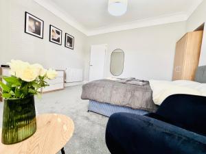 1 dormitorio con 1 cama y un jarrón de flores sobre una mesa en The Stunning house welcomes you en Liverpool