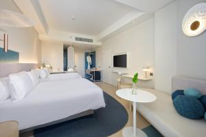 a bedroom with a large white bed and a couch at Centara Karon Resort Phuket - SHA Extra Plus in Karon Beach
