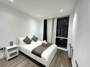 um quarto branco com uma cama e uma janela em Luxury 2 Bedroom Penthouse Near Central London em Londres