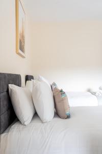 un mucchio di cuscini poggiati sopra un letto di Edgehill City Centre Haven By Icon Living Properties Short Lets & Serviced Accommodation Reading a Reading