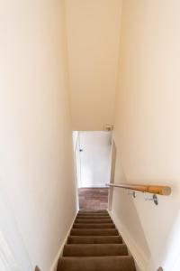 a staircase in a room with white walls and brown stairs at Edgehill City Centre Haven By Icon Living Properties Short Lets & Serviced Accommodation Reading in Reading