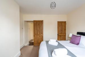 a bedroom with a bed with white sheets and purple pillows at Edgehill City Centre Haven By Icon Living Properties Short Lets & Serviced Accommodation Reading in Reading