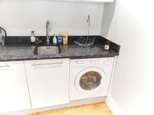 a kitchen with a sink and a washing machine at Modern Central Brighton patio flat - free parking! in Brighton & Hove