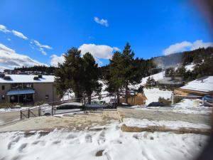 ein schneebedeckter Parkplatz mit Bäumen und einem Gebäude in der Unterkunft STUDIO COSY ISARD P2000 in Bolquere