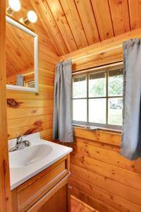 a bathroom with a sink and a window in a log cabin at Rustic Cabin with Pool Access in Bloomington