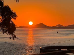 a sunset over the ocean with a boat in the water at Tranquil Escape - Koala Hotspot - 2 Bed 2 Bath Apt Spectacular Sea Views in Soldiers Point