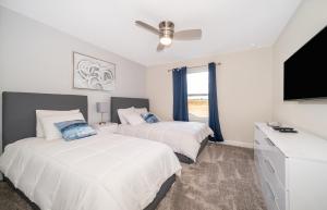 a bedroom with two beds and a flat screen tv at Luxury Townhouses 18 Minutes away from Disney! in Kissimmee