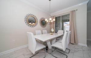 a dining room with a white table and white chairs at Luxury Townhouses 18 Minutes away from Disney! in Kissimmee