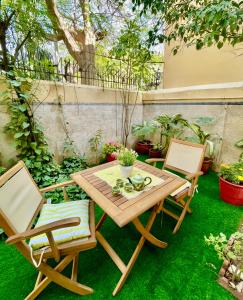 une table en bois et deux chaises sur une pelouse dans l'établissement Mohalla Rooftop Retreat, à Karachi