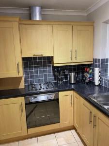 a kitchen with wooden cabinets and a stove top oven at Walnut Apartment Larne in Larne