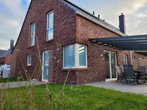 a brick house with a table and chairs on a patio at Nordseehus-HYGGE in Butjadingen