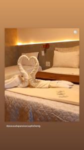 Habitación de hotel con 2 camas y toalla con forma de corazón en Paraíso Capitólio Suítes Pousada en Capitólio