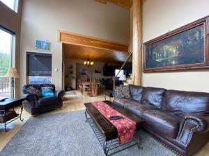 a living room with a leather couch and a table at Morrisey Chalet at Sun Peaks in Sun Peaks