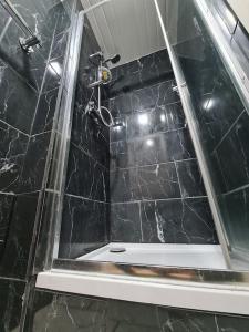 a bathroom with a shower with a black marble wall at Ideal Apartment close to the Hustle and Bustle in Ashton under Lyne