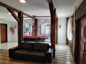 uma sala de estar com um sofá de couro e uma parede de vidro em Hibisco Home Hotel em Urubici