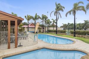 a swimming pool at a resort with palm trees at Discovery Parks - Bunbury Foreshore in Bunbury