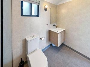a bathroom with a white toilet and a sink at BeachComber holiday house in Marengo +6 photos