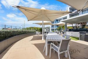 a table and chairs with an umbrella on a patio at Waterview Penthouse - Cote D'Azur Resort, Nelson Bay in Nelson Bay