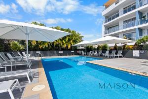 a swimming pool with chairs and umbrellas next to a building at Waterview Penthouse - Cote D'Azur Resort, Nelson Bay in Nelson Bay