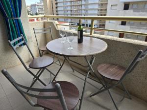 una mesa con 2 sillas y una botella de vino en el balcón en Sea ​​apartments, en La Pineda