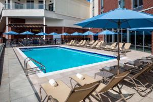 a swimming pool with chairs and a blue umbrella at Hyatt Place Long Island East End in Riverhead