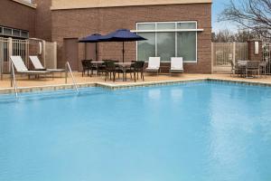 une grande piscine bleue avec des chaises et un parasol dans l'établissement Hyatt Place Sugar Land, à Sugar Land