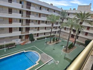 un gran edificio de apartamentos con piscina y palmeras en Sea ​​apartments, en La Pineda