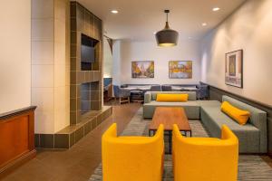 a living room with a couch and a table and yellow chairs at Hyatt Place Madison/Downtown in Madison