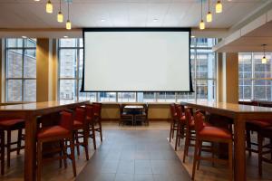 a large screen in a room with tables and chairs at Hyatt Place Minneapolis/Downtown in Minneapolis