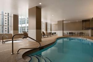 einen Pool in einem Hotel mit Stühlen und Tischen in der Unterkunft Hyatt Place Minneapolis/Downtown in Minneapolis