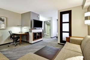a living room with a couch and a desk and a tv at Hyatt Place Minneapolis Eden Prairie in Eden Prairie