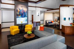 sala de estar con sofá azul y sillas amarillas en Hyatt Place Roanoke Airport / Valley View Mall, en Roanoke