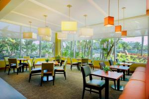 un restaurant avec des tables, des chaises et des fenêtres dans l'établissement Hyatt Place Manati, à Manati