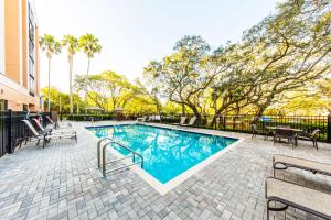 a swimming pool with chairs and a fence and trees at Hyatt Place Tampa Busch Gardens in Tampa