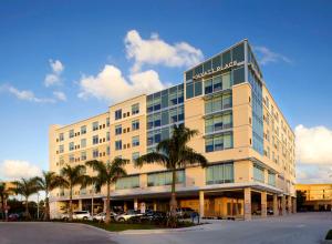 een groot gebouw met palmbomen ervoor bij Hyatt Place Miami Airport East in Miami