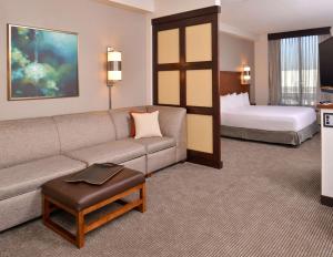 a living room with a couch and a bed at Hyatt Place Garden City in Garden City