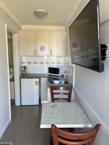a kitchen with white appliances and a table and chairs at Mandurah Coastal Holiday Park in Mandurah