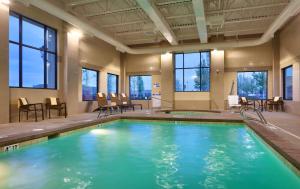 - une piscine dans un bâtiment avec des chaises et des tables dans l'établissement Hyatt Place Salt Lake City Farmington Station Park, à Farmington